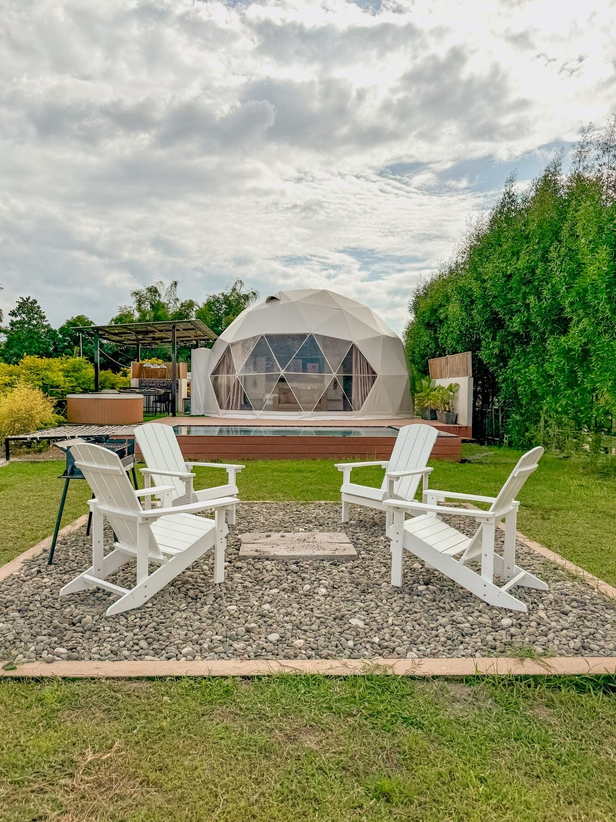 A fire pit ringed with chairs on the lawn beside a dome